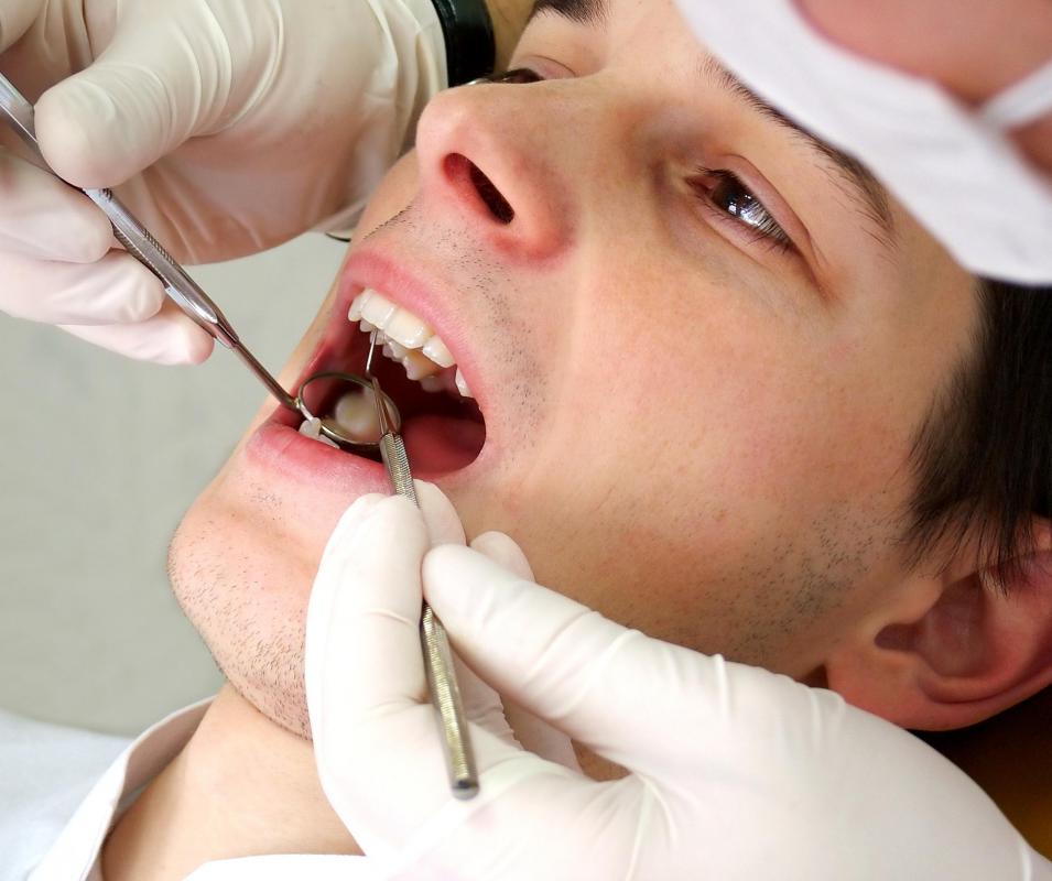 A dental hygienist, an allied health professional, cleans a patient's teeth.