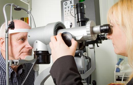 An optometrist assistant may help prepare a patient for their eye exam.
