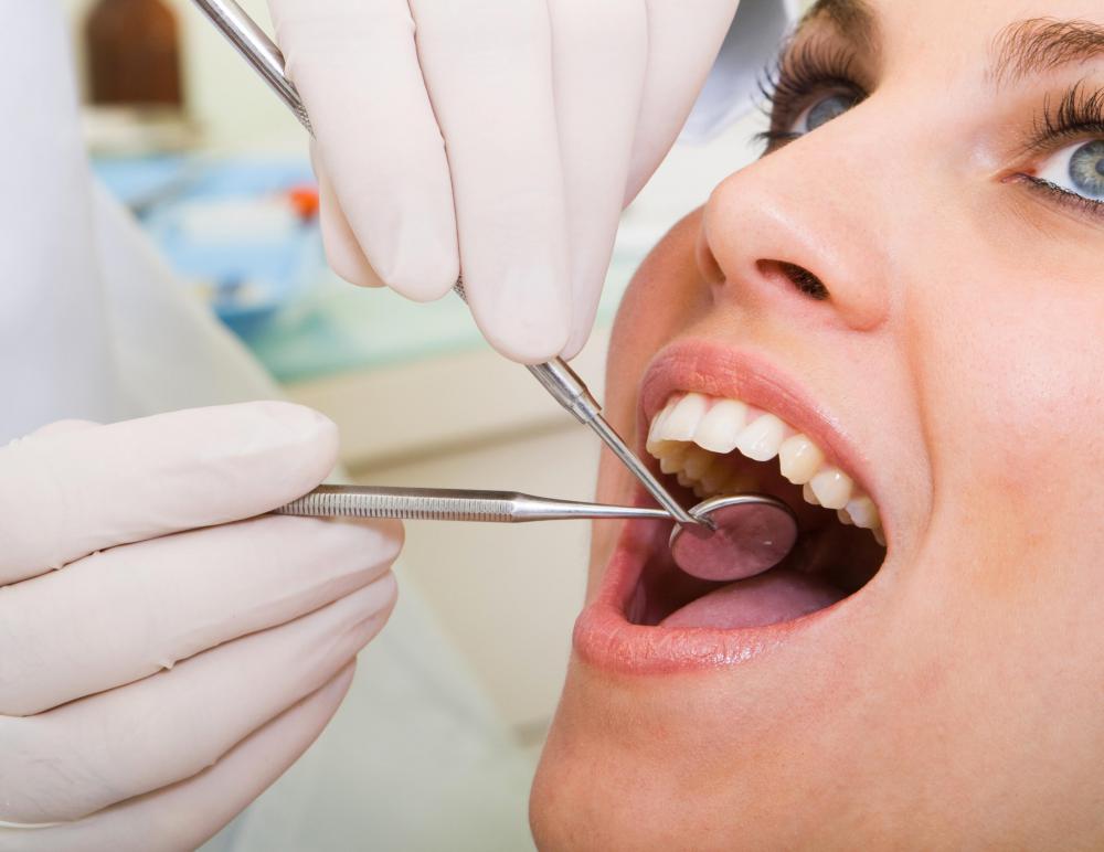 A woman having a tooth cleaning from a dental hygienist, a type of paraprofessional.