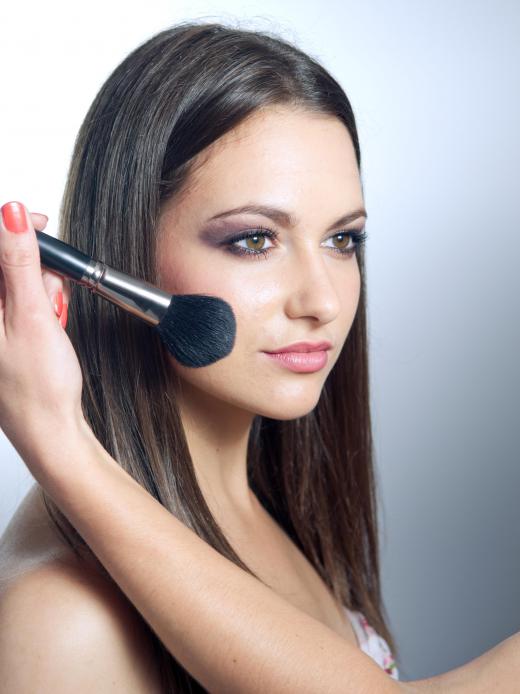 A beauty expert applies makeup to a woman's face.