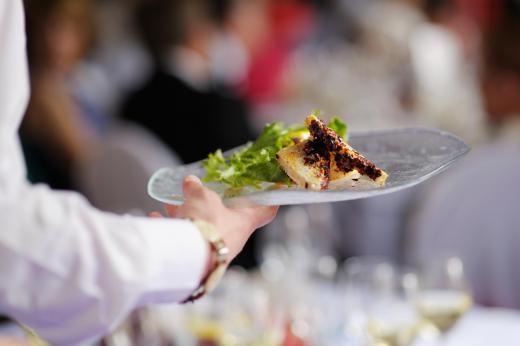 A banquet server tends to the guests during a meal.