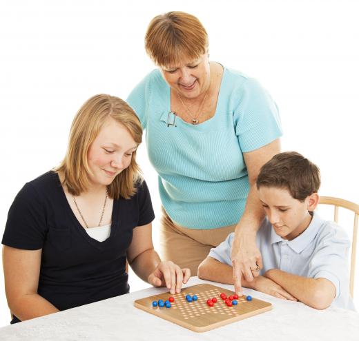 A psychiatric assistant may socialize with patients through the playing of board games.