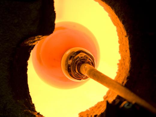 A glass blower heating glass in a kiln.