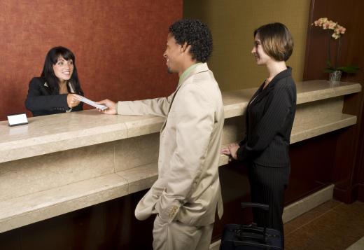 A hotel receptionists checks guests into a hotel.