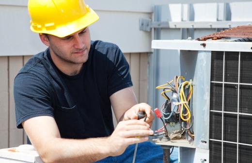 A maintenance man making repairs to an air conditioning unit.