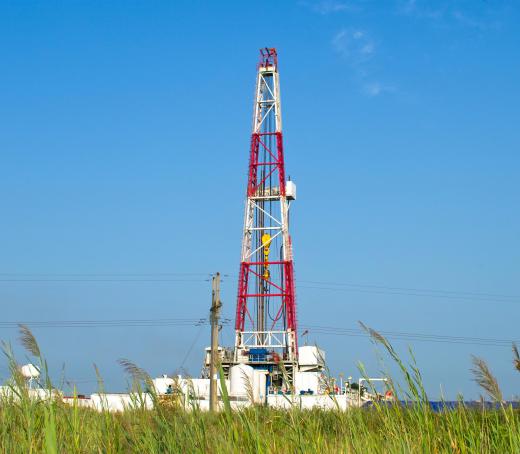 A red and white oil derrick. A roughneck works in an oil field.