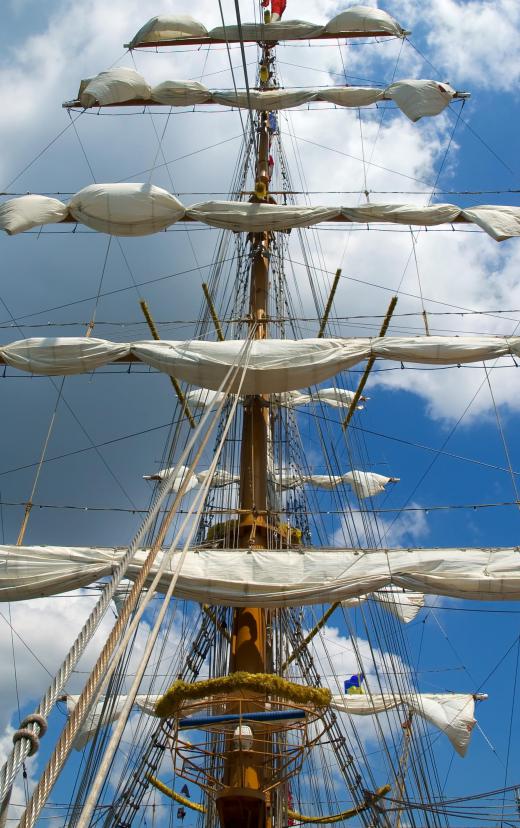 A marine rigger works with a ship's rigging to adjust the sails.