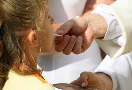 Priest giving the Holy Communion to a young girl.