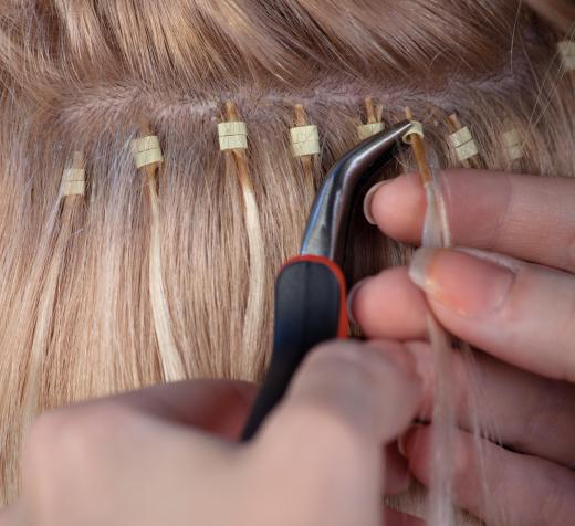 A hairstylist putting in hair extensions.