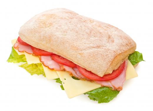 Sandwich made with ciabatta bread, ham, lettuce, Swiss cheese, and tomatoes.