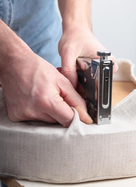 An upholsterer may fasten upholstery fabric by using a staple gun.