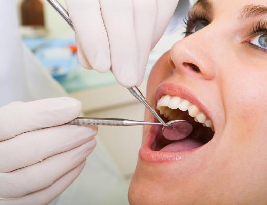 A woman having a tooth cleaning from a dental hygienist, a type of paraprofessional.